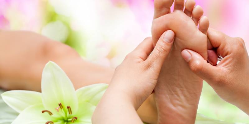Close up of therapist's hands massaging female foot.